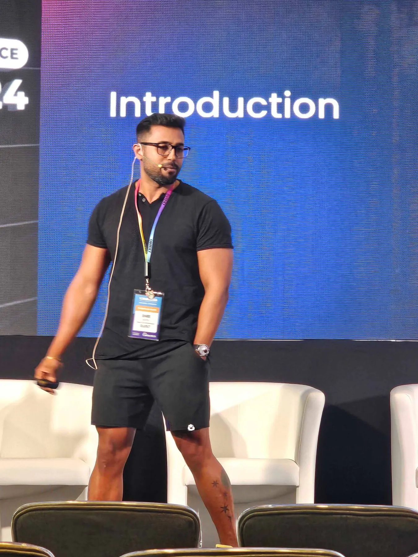 Dhee walking the stage in front of a large Introduction slide.